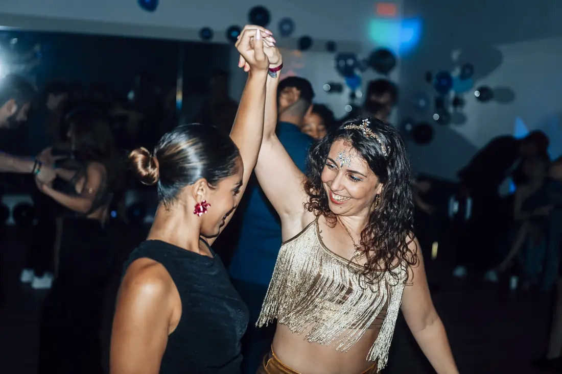 Two women dancing and laughing at a BSO social